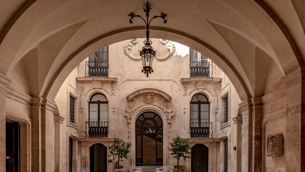 Un patio arqueado con una escalera central, paredes de piedra y un colgador de luz.