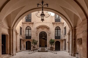 Un patio arqueado con una escalera central, paredes de piedra y un colgador de luz.