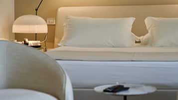 A hotel room with a bed, a nightstand with a lamp, and a small table with a remote control.