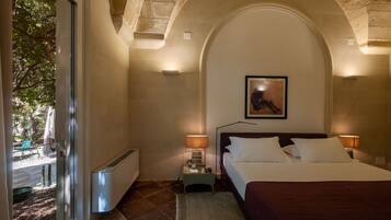 Habitación de hotel con cama, lámparas de noche, radiador y vistas al exterior.