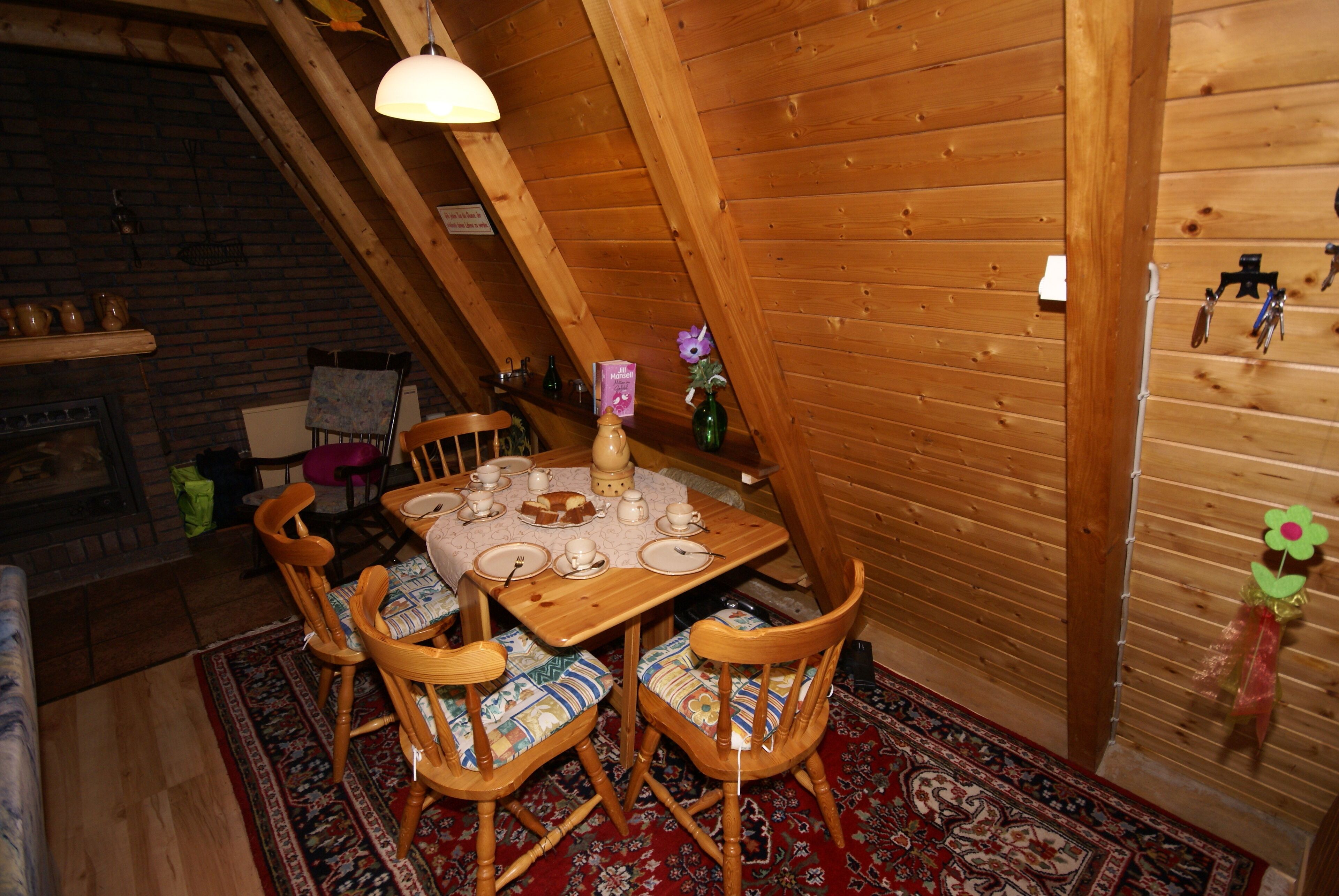 A dining area with a wooden table set for four, surrounded by chairs with patterned cushions.