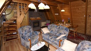 A cozy log cabin interior with a wooden staircase, a fireplace, a sofa set, and a dining area. - **** Only roof house **** lovingly furnished    (Wiefelstede)