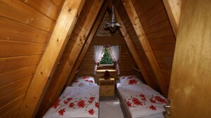 A small attic bedroom with two single beds, a wooden ceiling, a window with curtains, and a small Christmas tree. - **** Only roof house **** lovingly furnished    (Wiefelstede)
