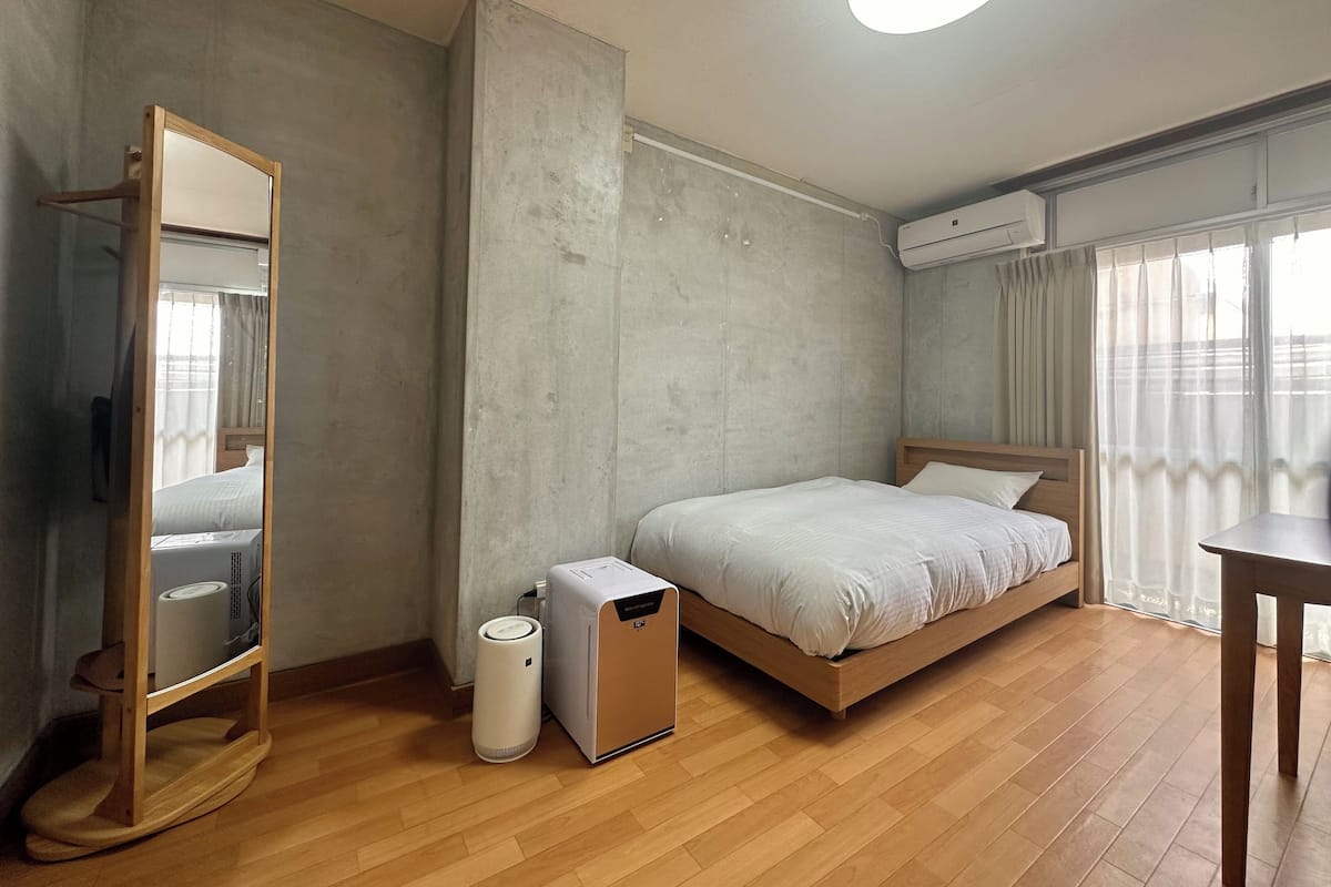 Ein modernes Hotelzimmer mit einem Holzbett, einem Nachttisch, einem großen Spiegel und einer Klimaanlage.