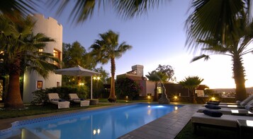 Una piscina al aire libre, sillones reclinables de piscina