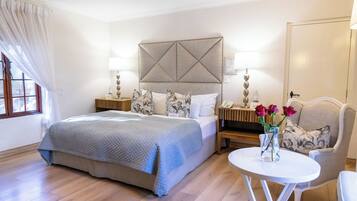 Habitación de hotel con una cama grande, dos mesitas de noche con lámparas, una mesita redonda y una silla.