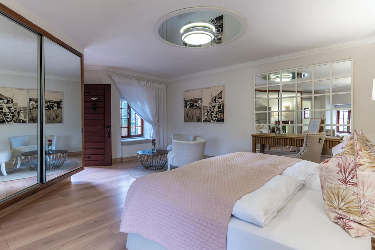 A modern hotel room with a large bed, a round mirror, a desk, and a chair.