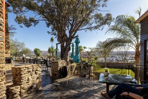Un patio con paredes de piedra, una mesa con cubierta de vidrio y vistas a la ciudad.