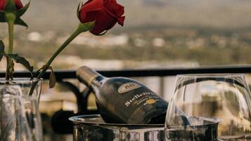 A table with a wine bottle, a wine glass, and a vase with a rose.