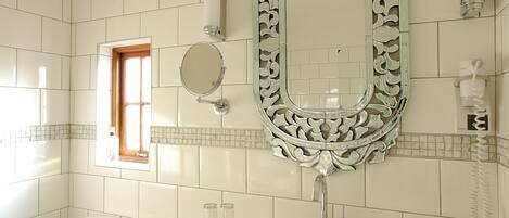 A bathroom with a white toilet, a sink with a mirror above it, and a window with a wooden frame.