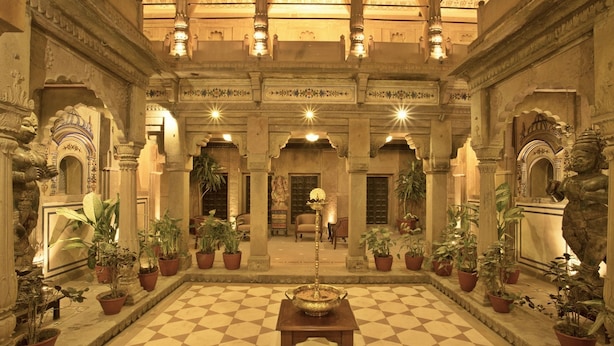 A spacious courtyard with a checkered floor, potted plants, and a central table.