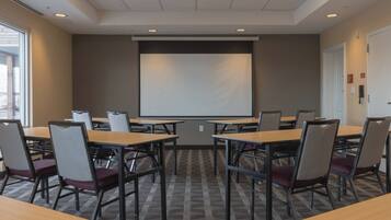 A conference room with a projector screen, tables, and chairs arranged for meetings.