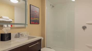 Een badkamer met een glazen douche, een wastafel met een handdoekrek en een spiegel.