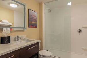 A bathroom with a glass shower, a sink with a towel rack, and a mirror.