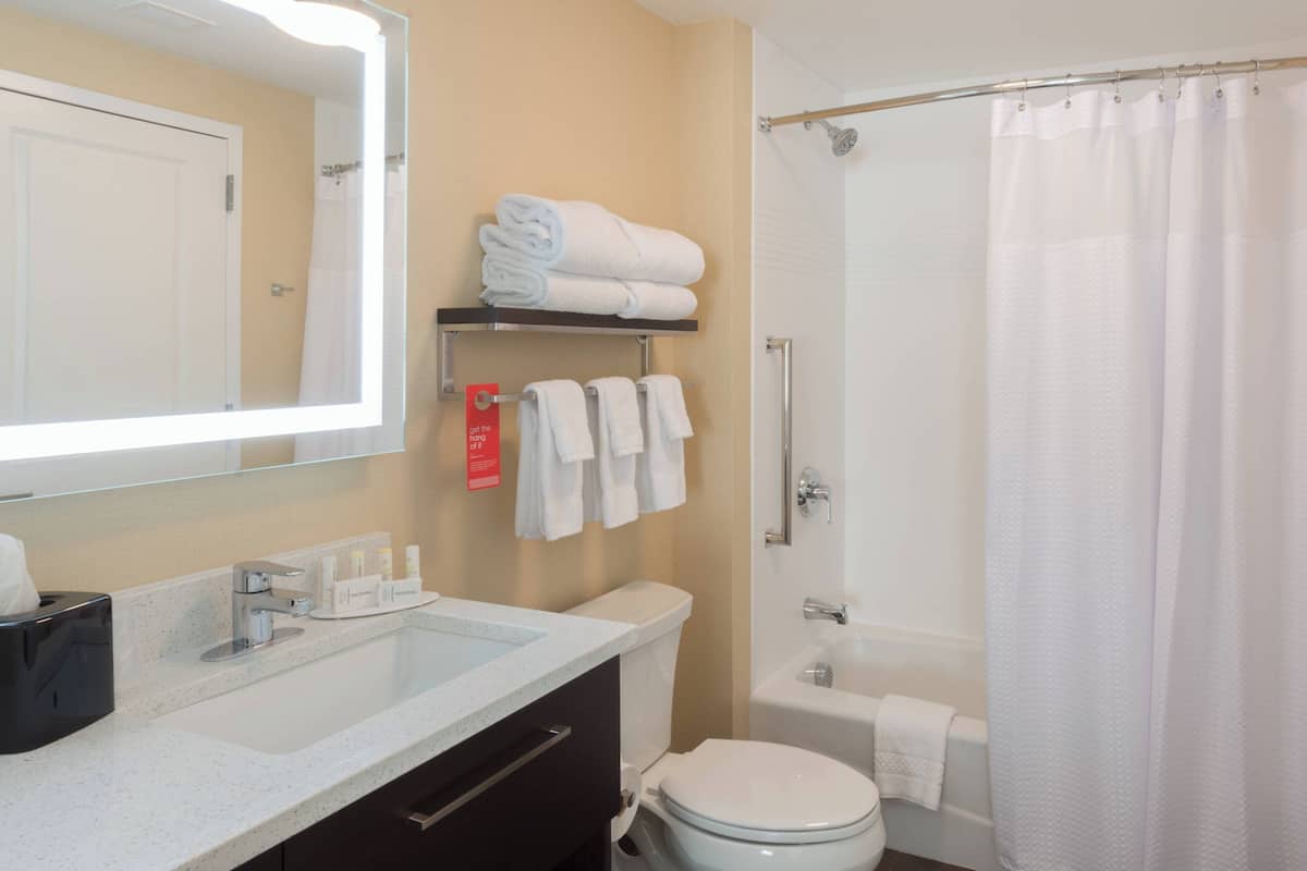 A bathroom with a sink, mirror, toilet, and shower curtain.