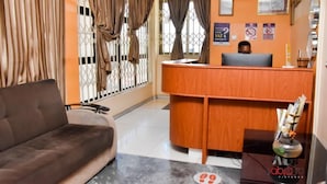 A reception area with a wooden desk, a sofa, and a decorative vase. - Dikab Hotel (Accra)