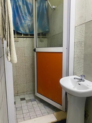 A bathroom with a shower, a sink, and a tiled floor. - Dikab Hotel (Accra)