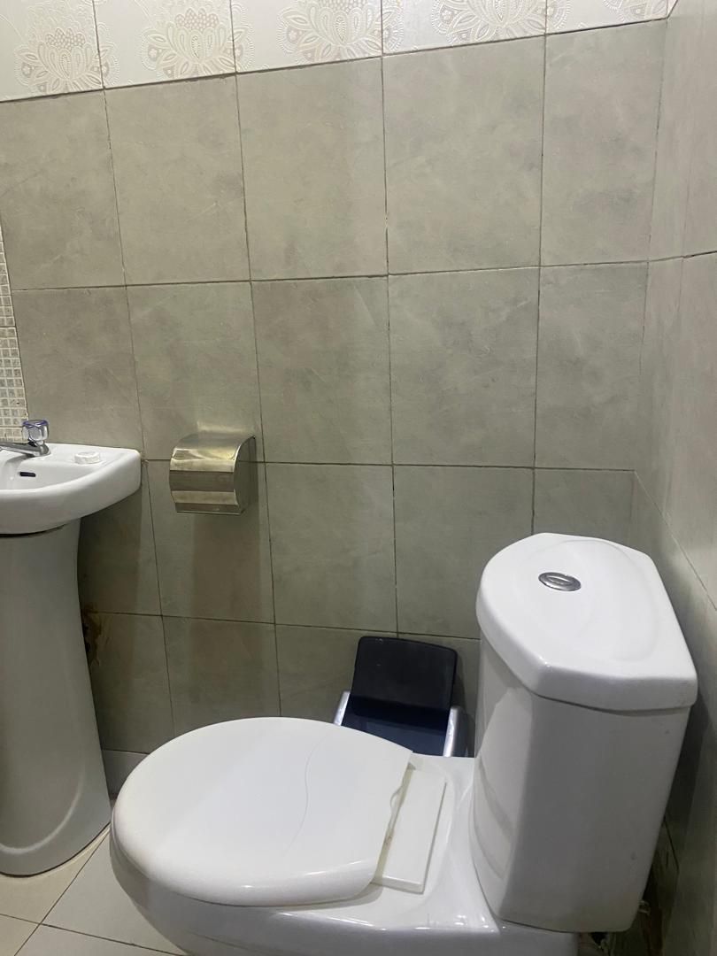 A bathroom with a toilet, a sink, and a toilet paper holder.