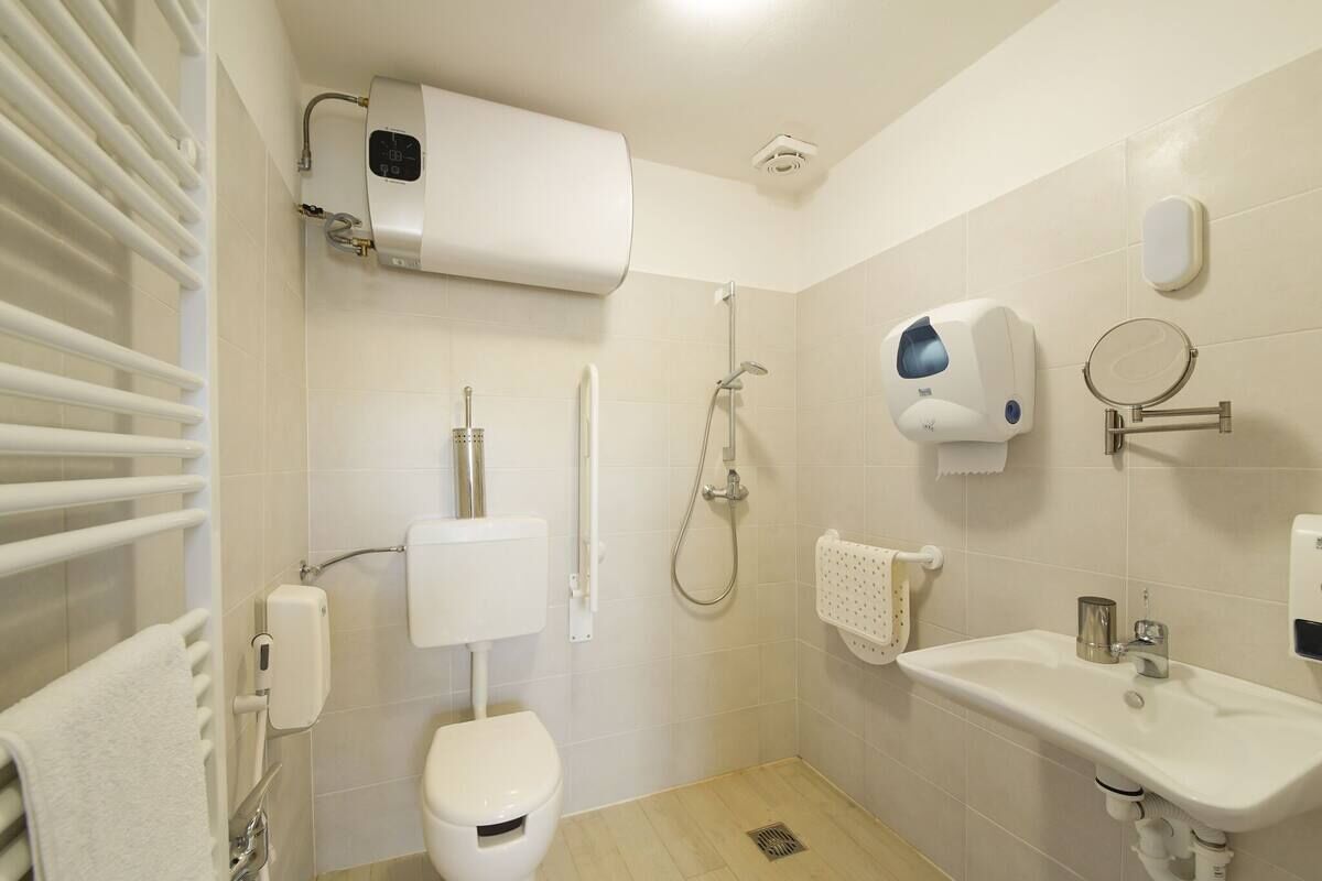 A bathroom with a toilet, a sink, a shower, and a towel rack.