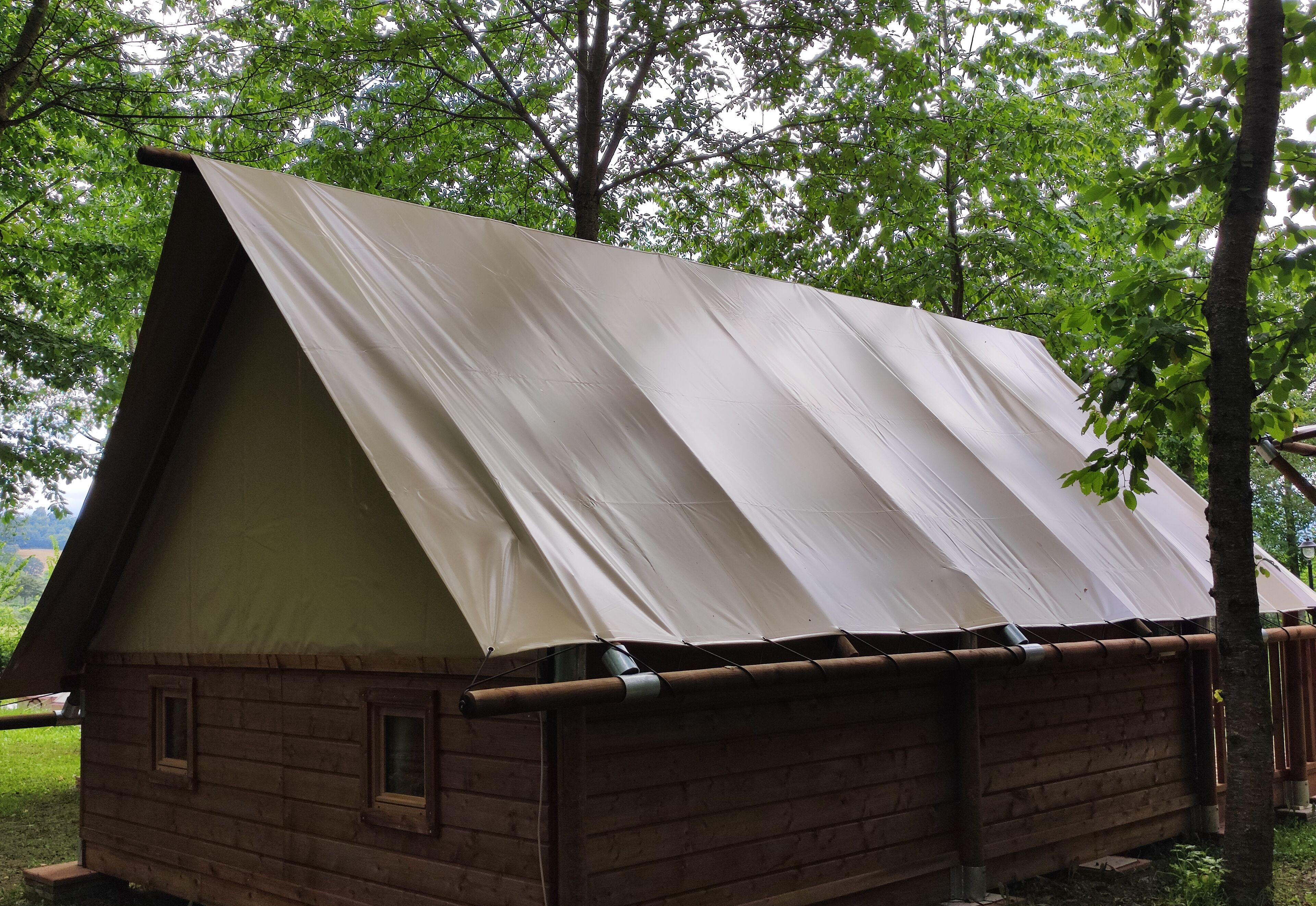 Une petite cabane en bois, dotée d’un toit à deux versants et d’un auvent en toile.