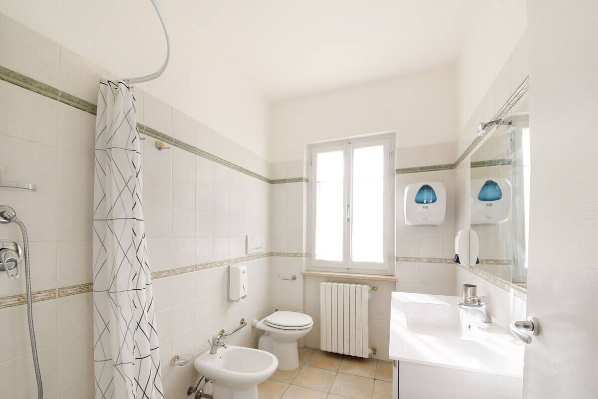 A bathroom with a shower, toilet, sink, and a window.