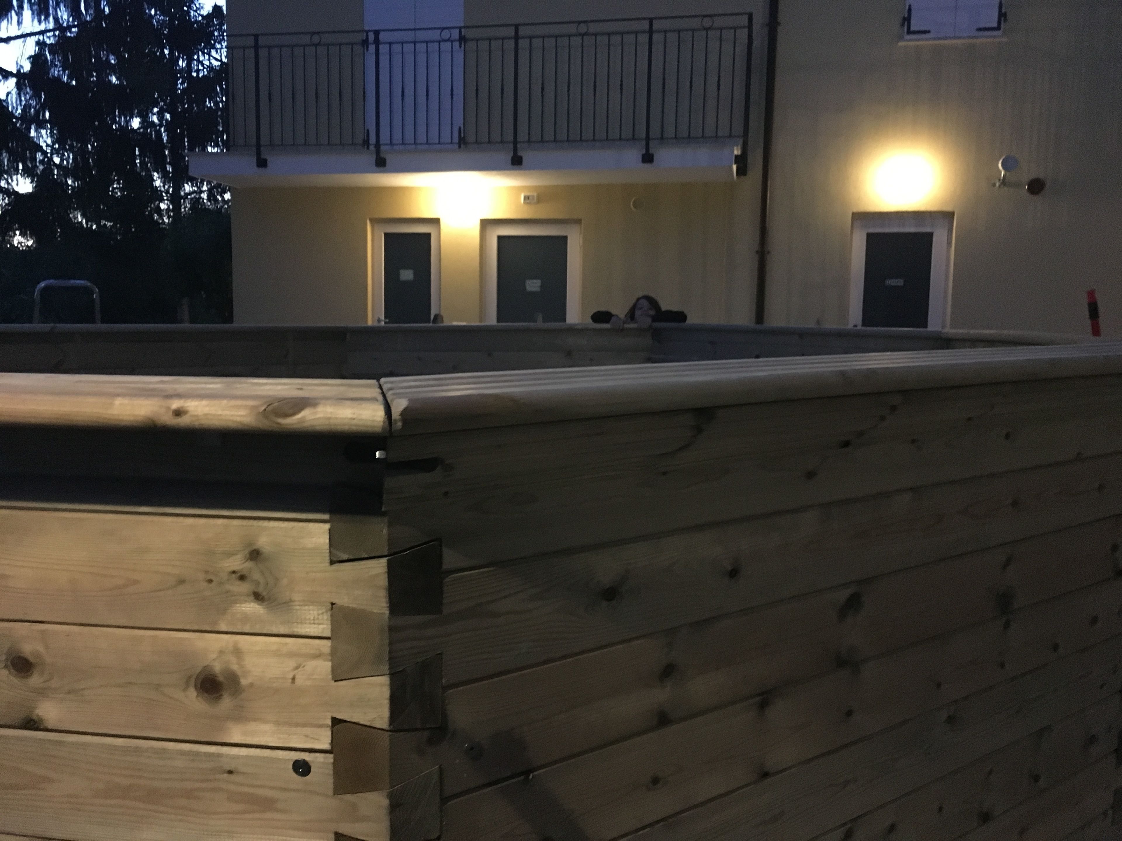 A building with a wooden deck, a balcony, and doors.