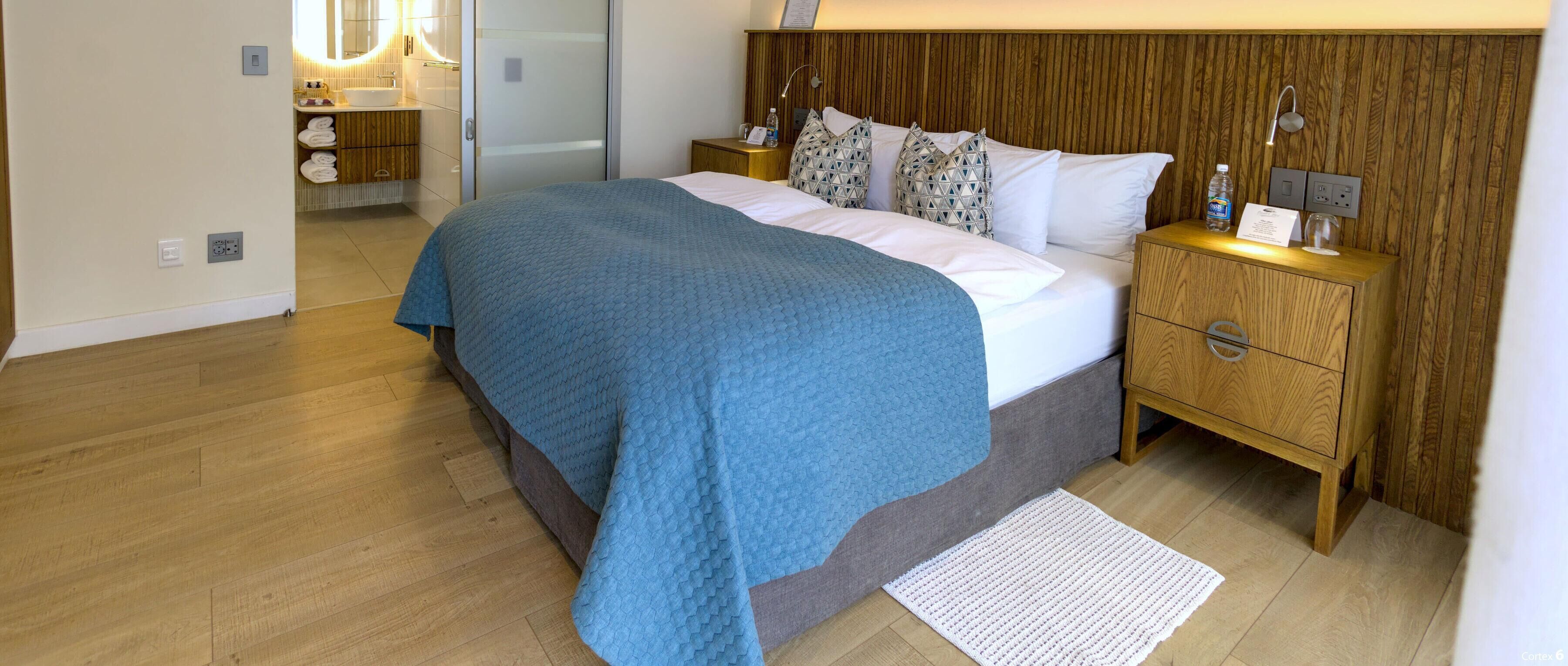 Une chambre moderne avec un grand lit, une tête de lit en bois, des tables de chevet avec des lampes et une armoire intégrée.