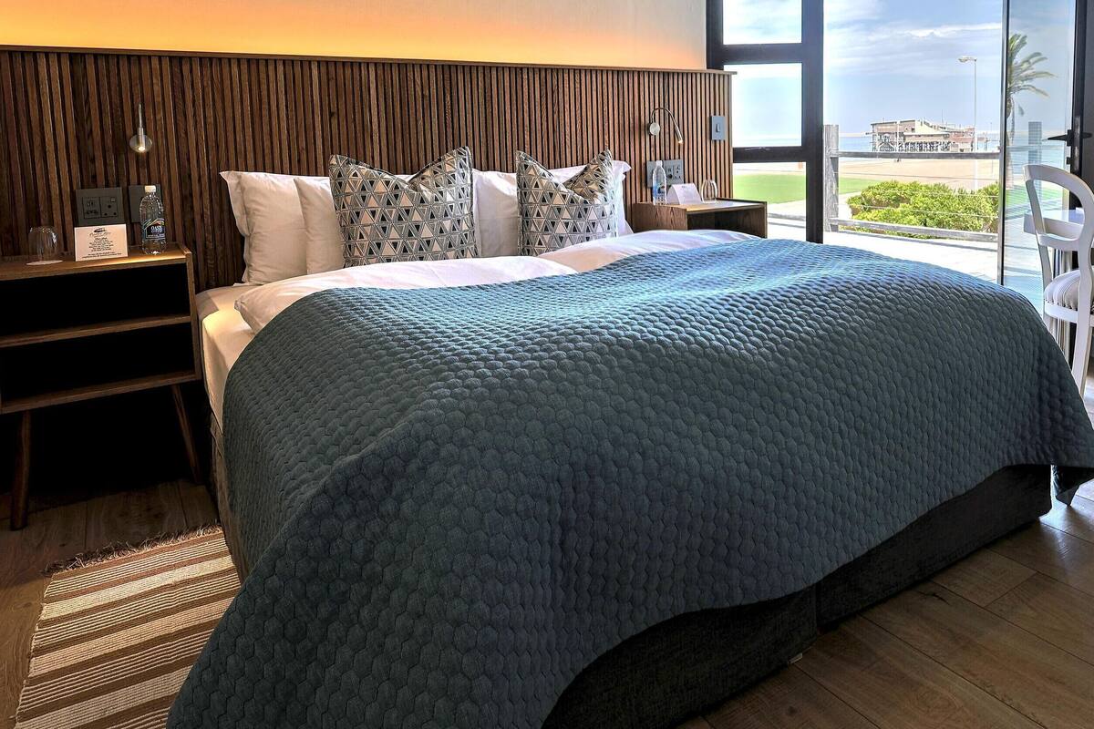 A bedroom with a large bed, a desk, and a view of the beach.