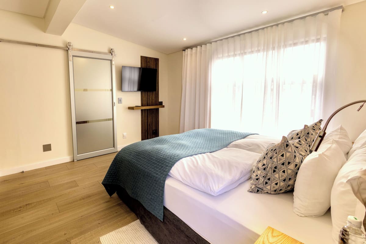 A bedroom with a bed, a TV mounted on the wall, and a sliding door.