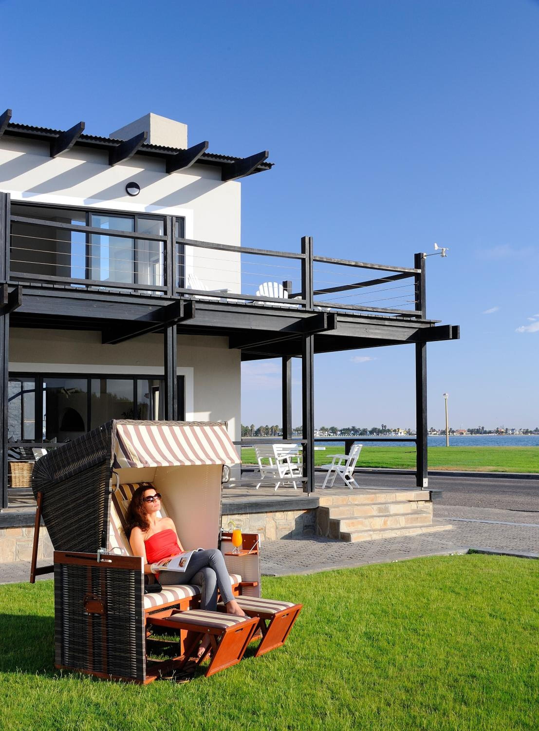 Una casa moderna con un área de estar cubierta al aire libre, una piscina y vista al mar.