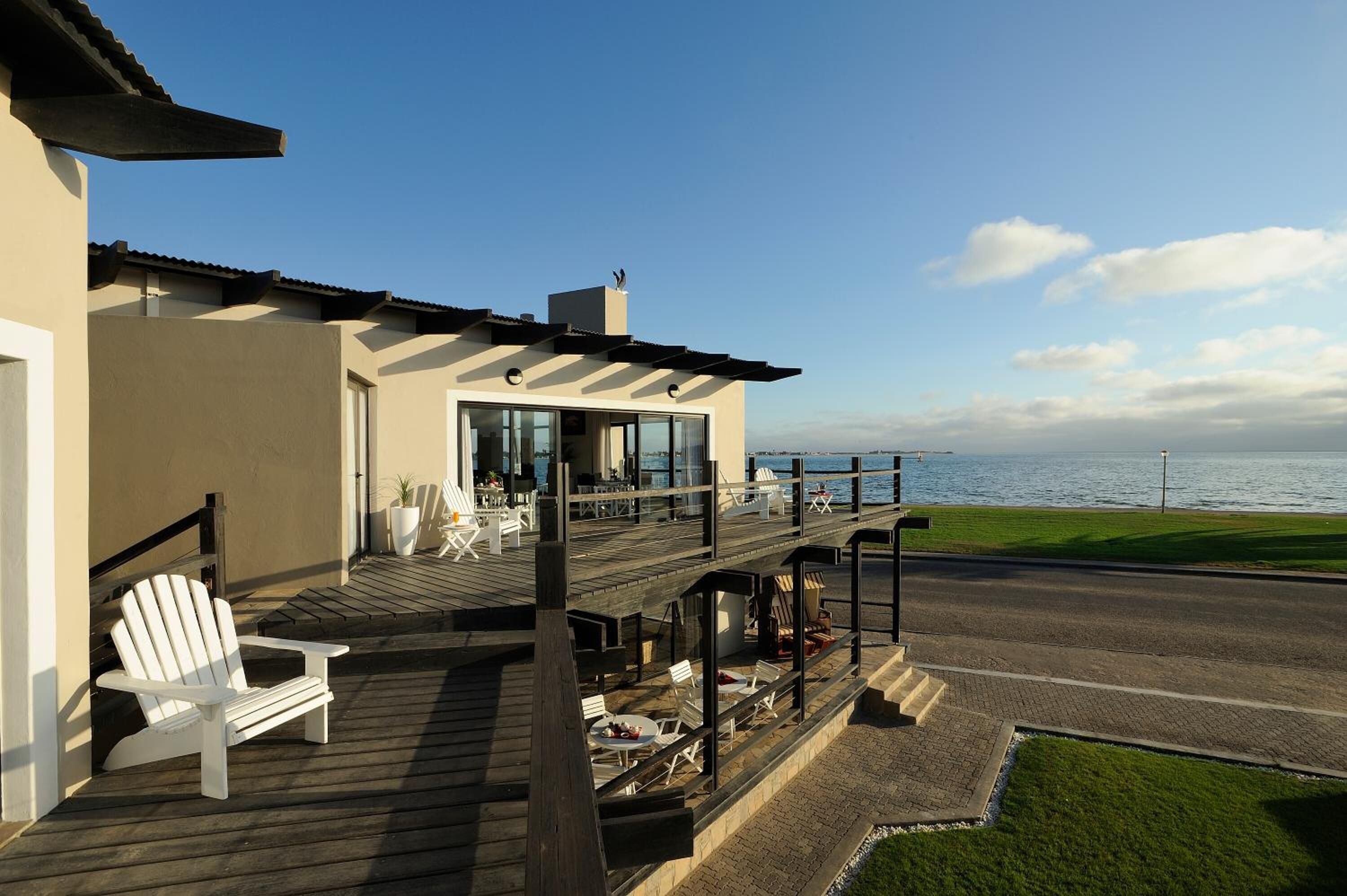 Ein modernes Haus mit einer Terrasse mit Blick auf ein Gewässer, inklusive Gartenmöbeln und Meerblick.