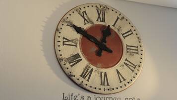A wall clock with Roman numerals and a quote below it.