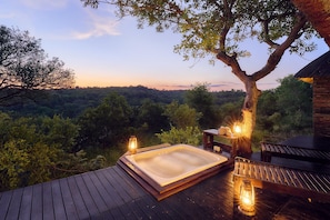 Un jacuzzi en una terraza de madera con vistas a un paisaje boscoso.