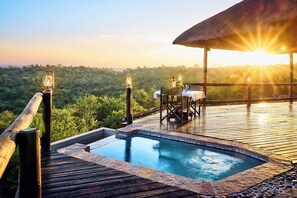 A wooden deck with a hot tub, a table with chairs, and a thatched roof structure. - Parsons Hilltop Safari Camp (Hoedspruit)