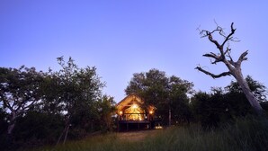 Eine Holzhütte mit Veranda, umgeben von Bäumen und Gras.
