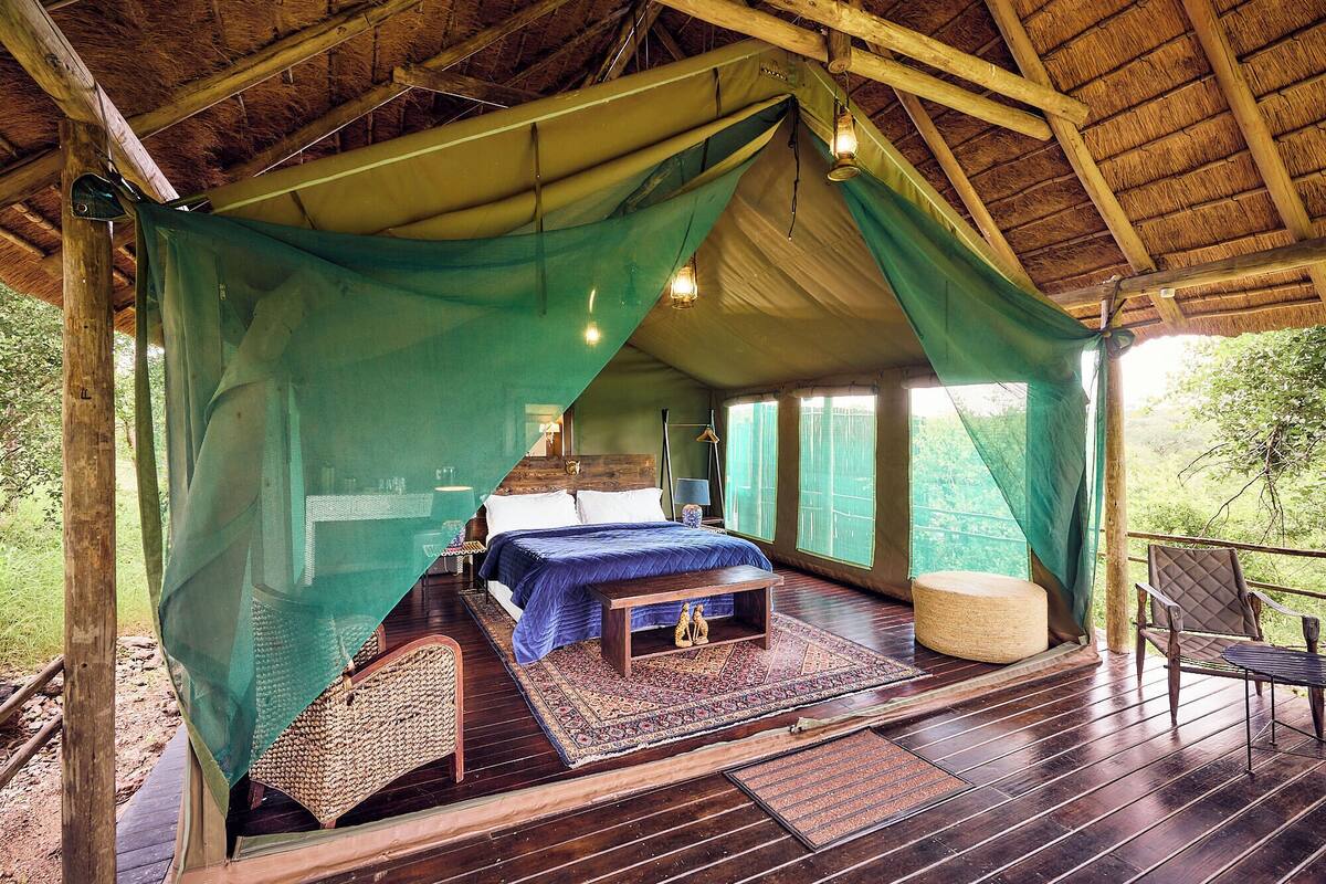 Een tent met een bed, een klein tafeltje en een bank.