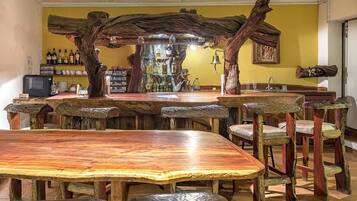 A rustic bar area with wooden furniture and a shelf of bottles.