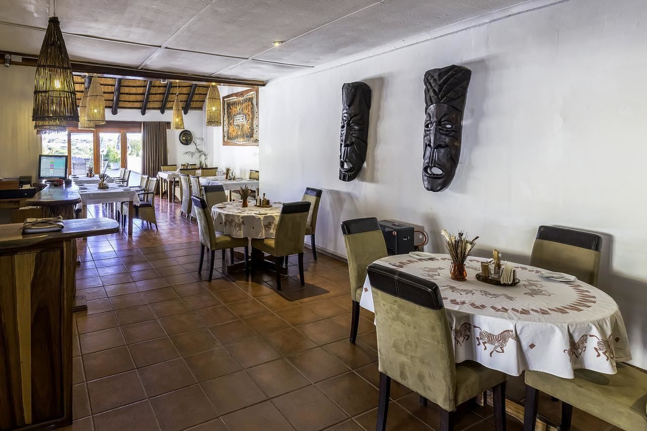 Un restaurante con una decoración rústica, que presenta mesas y sillas de madera, una zona de bar y máscaras decorativas en las paredes.