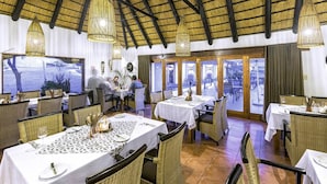 A restaurant with high ceilings and natural light, featuring wicker furniture and a view of the outdoors. - Trans Kalahari Inn (Windhoek)
