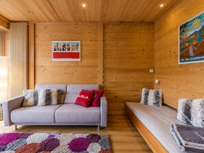Una habitación acogedora con un sofá, un banco y una alfombra colorida.