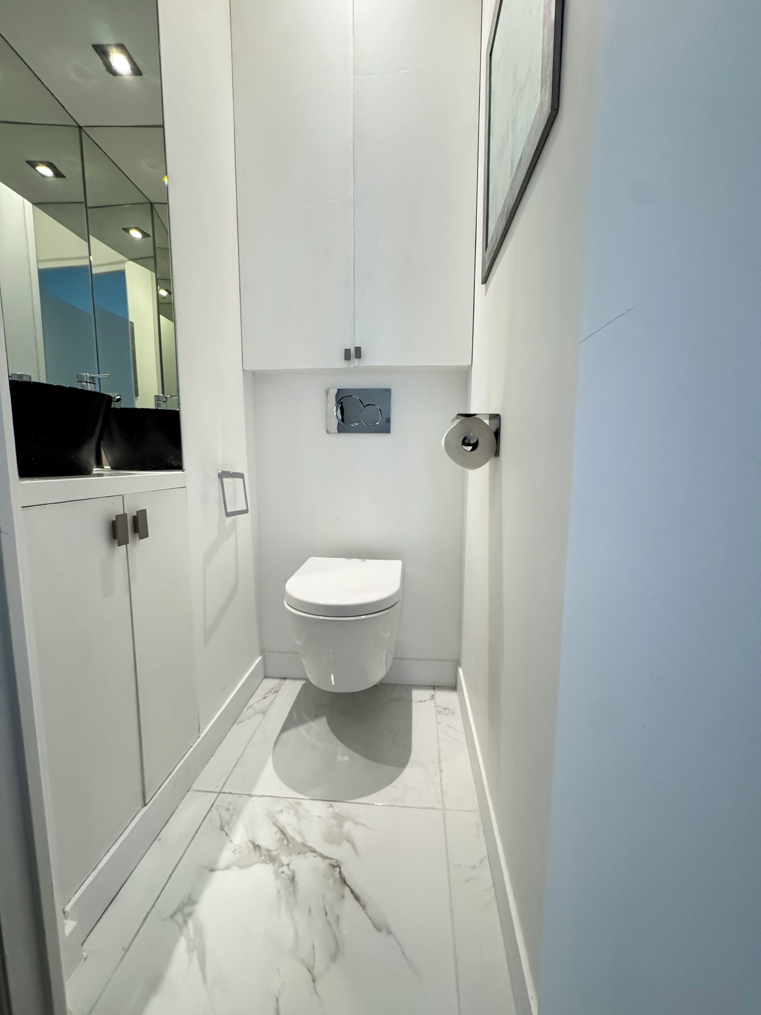 A modern bathroom with a white toilet, a glass shower enclosure, and a marble-tiled floor.