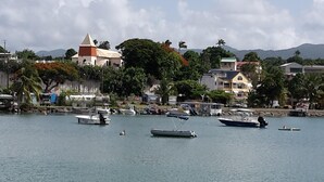 A marina with several boats docked, a church with a red roof, and residential buildings along the waterfront. - Creole villa with pool in tropical garden   (Sainte Rose)