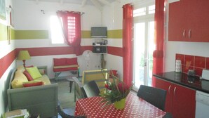 Un espacio habitable compacto con comedor, kitchenette y un sofá con cojines.