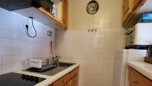 A compact kitchen with a stove, sink, and wooden cabinets. - Tignes: 2-room apartment 41m², 500m from slopes, southwest balcony, wifi, 4-5 pers. (Tignes)