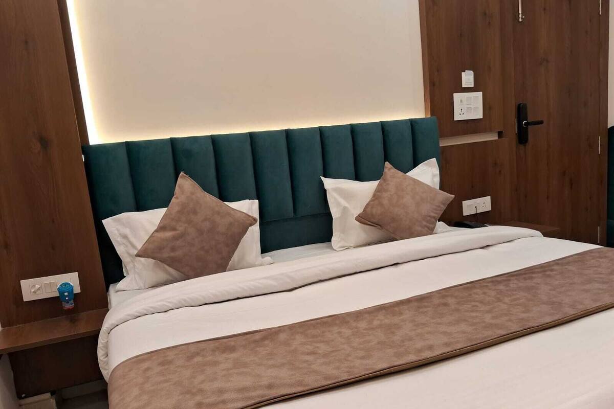 Una cama bien hecha con cabecera color aguamarina, almohadas blancas y marrones, y una manta marrón.