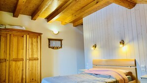 Un dormitorio con una cama de madera, un armario y un espejo fijado a la pared.
