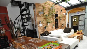 A modern living room with a wooden dining table, clear chairs, a white sofa, and a staircase. - * THE ATYPICAL LOFT * (Nancy)