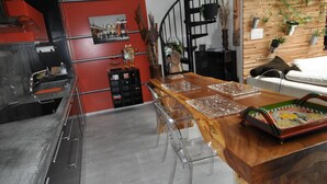 A modern kitchen with a wooden island, clear chairs, and a black spiral staircase. - * THE ATYPICAL LOFT * (Nancy)