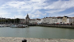 Une promenade au bord de l’eau avec des bateaux, une tour historique et des bâtiments qui bordent la rivière.
