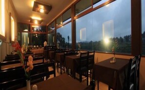 A restaurant with a view of the landscape through large windows. - Lemon Hotel (Lembang)